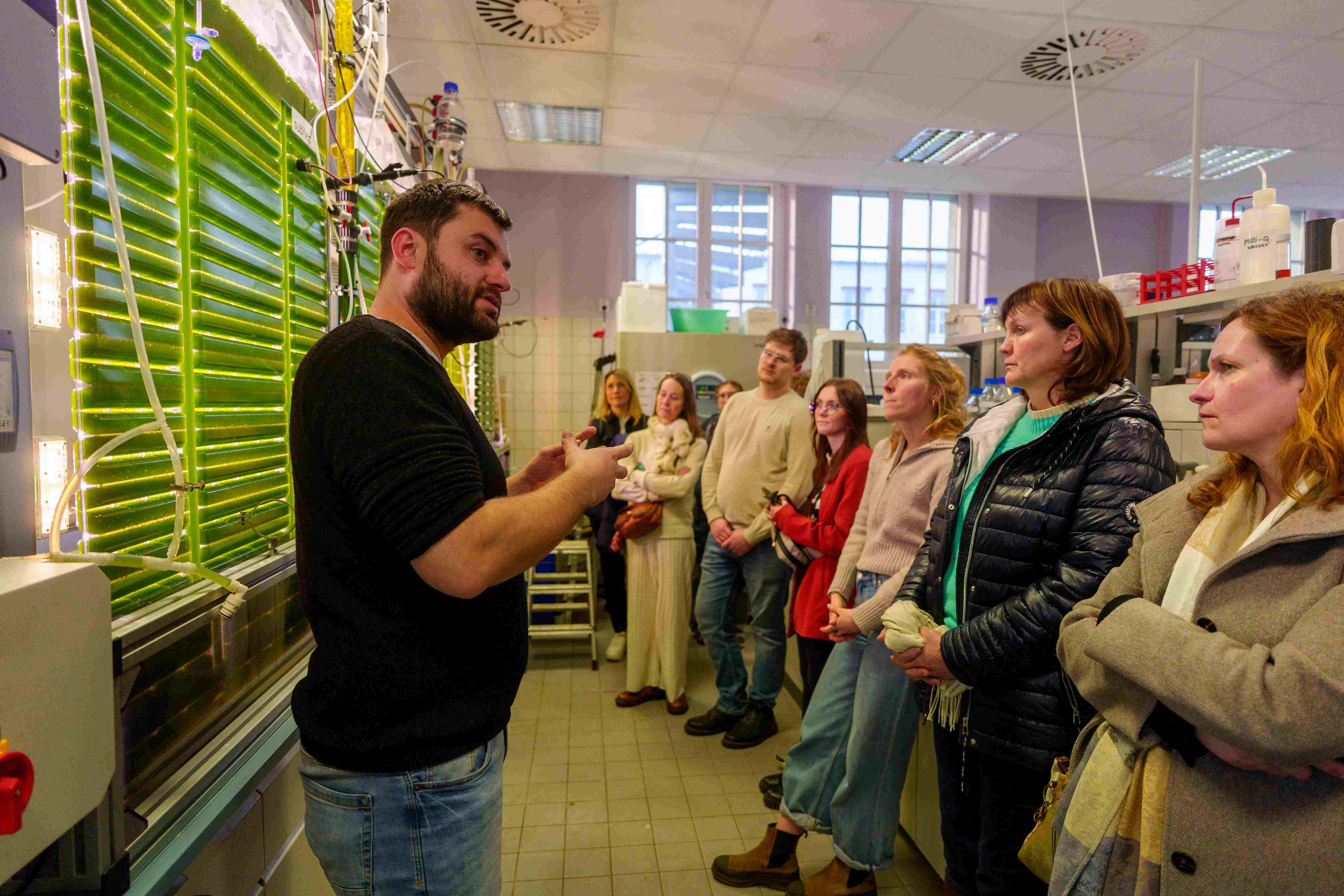 Gruppe von Personen in einem Labor zeigt Auftakt des Netzwerks Algahub und Präsentation eines Algenbioreaktors zur Produktion von Algen-Öl