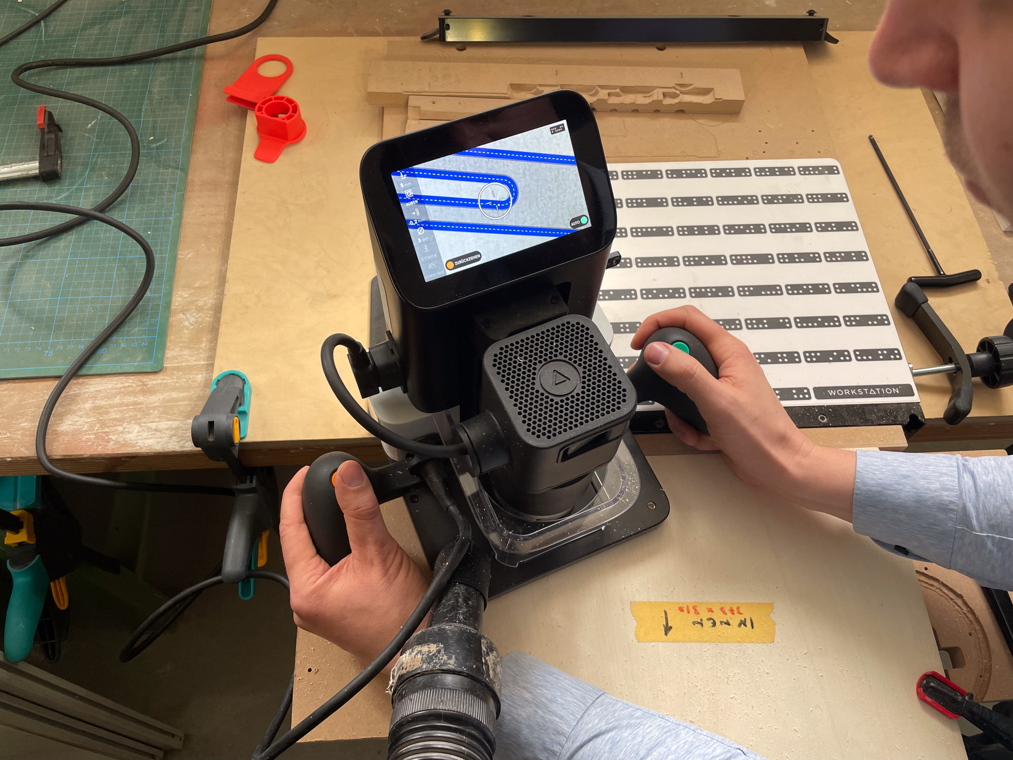 Foto zeigt Martin Wiesner am Schreibtisch bei der Konzeption eines modularen Möbelsystems mit Hilfe einer handgeführten Oberfräse, die über einen digitalen Plan gefüttert wird 