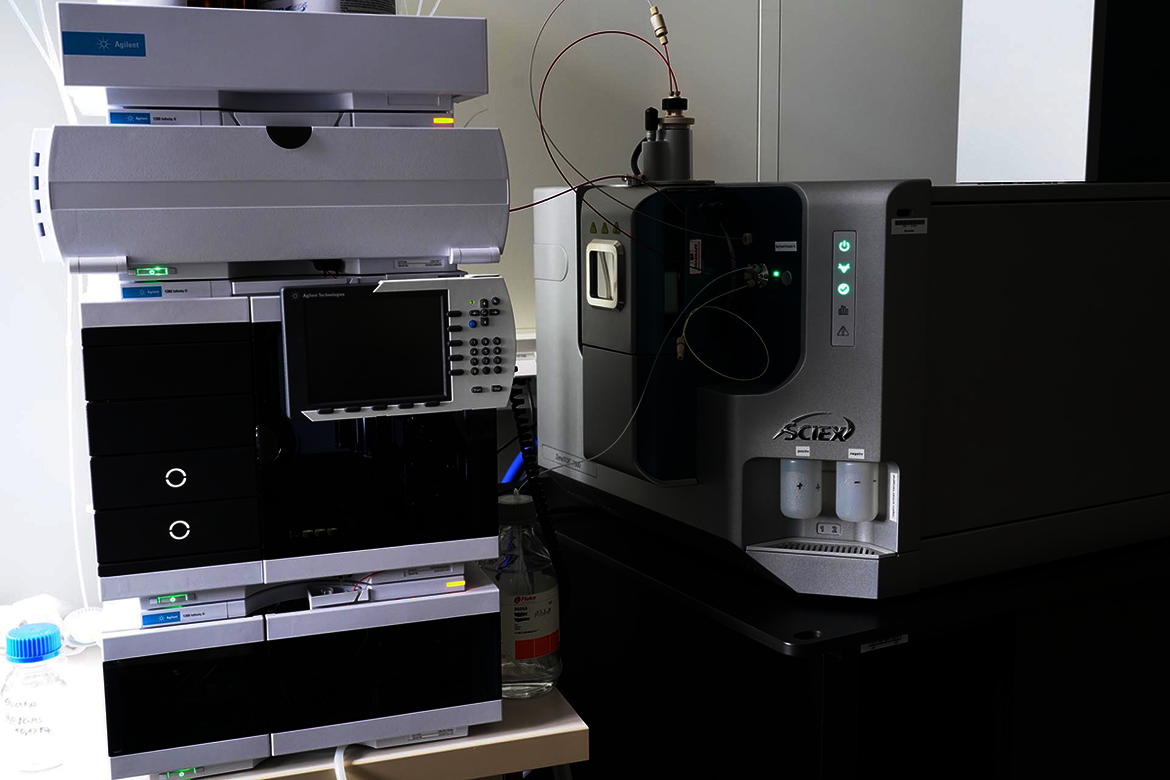 Zwei hochmoderne Laborgeräte stehen nebeneinander auf einem Tisch. Links ein großes Chromatographiegerät mit Bedienfeld, Displays und mehreren Schubladen. Rechts ein Massenspektrometer mit integriertem Probengeber und digitalem Steuerpanel. Beide Geräte sind für analytische Chemie und präzise Stoffuntersuchungen ausgelegt.