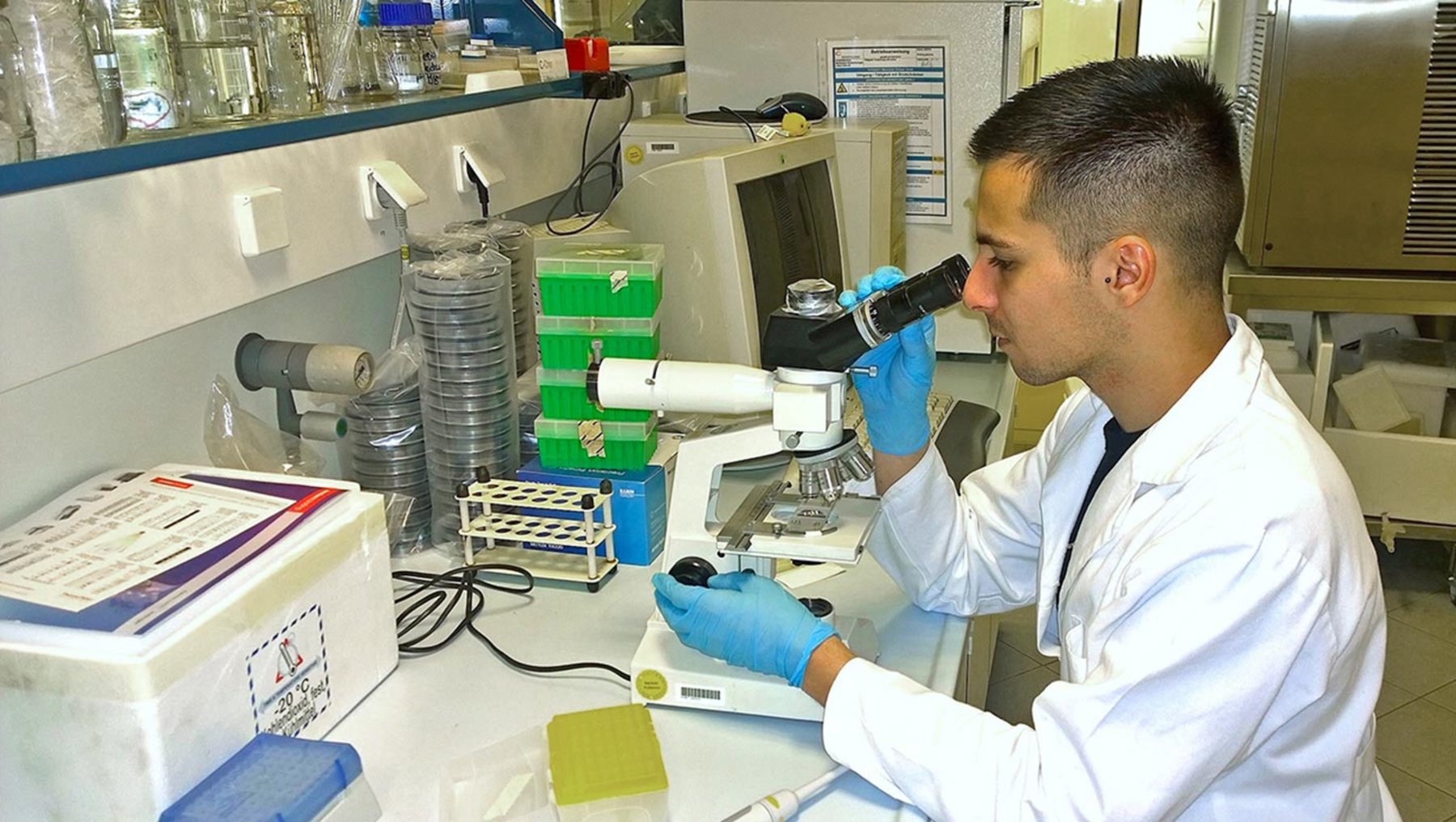 Studierender im Labor am Mikroskop untersucht Probe