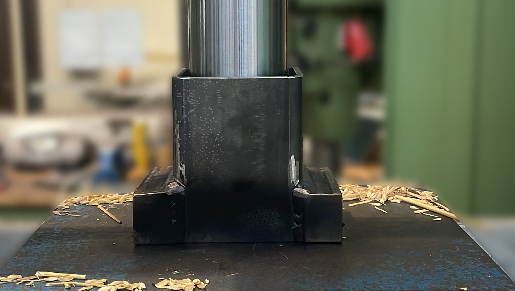 Eine Metallpresse drückt ein Stahlprofil in die Mitte einer flachen Metallplatte, wodurch sich die Spreu gepresst wird.