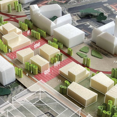 Modell einer futuristischen Stadtplanung mit begrünten Hochhäusern, weißen Gebäudeblöcken und durchgehenden grünen Korridoren, die durch rote Verkehrswege verbunden sind.