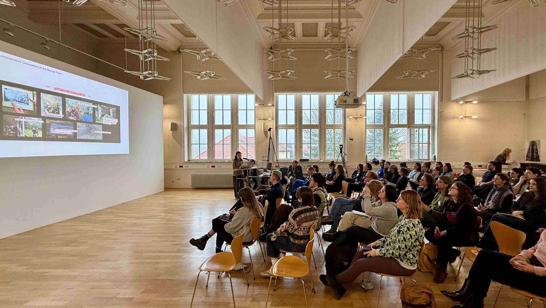 Symbolbild Promovieren im Design zeigt Vortrag mit Publikum in einem historischen Saal am Bauhaus Dessau