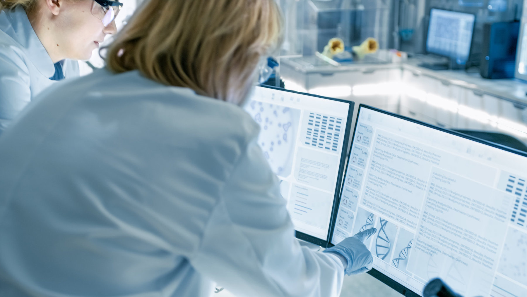 Zwei Laborassistenten in weißer Kleidung und Handschuhen analysieren genetische Daten auf einem Bildschirm mit DNA-Diagramm und Sequenzinformationen.