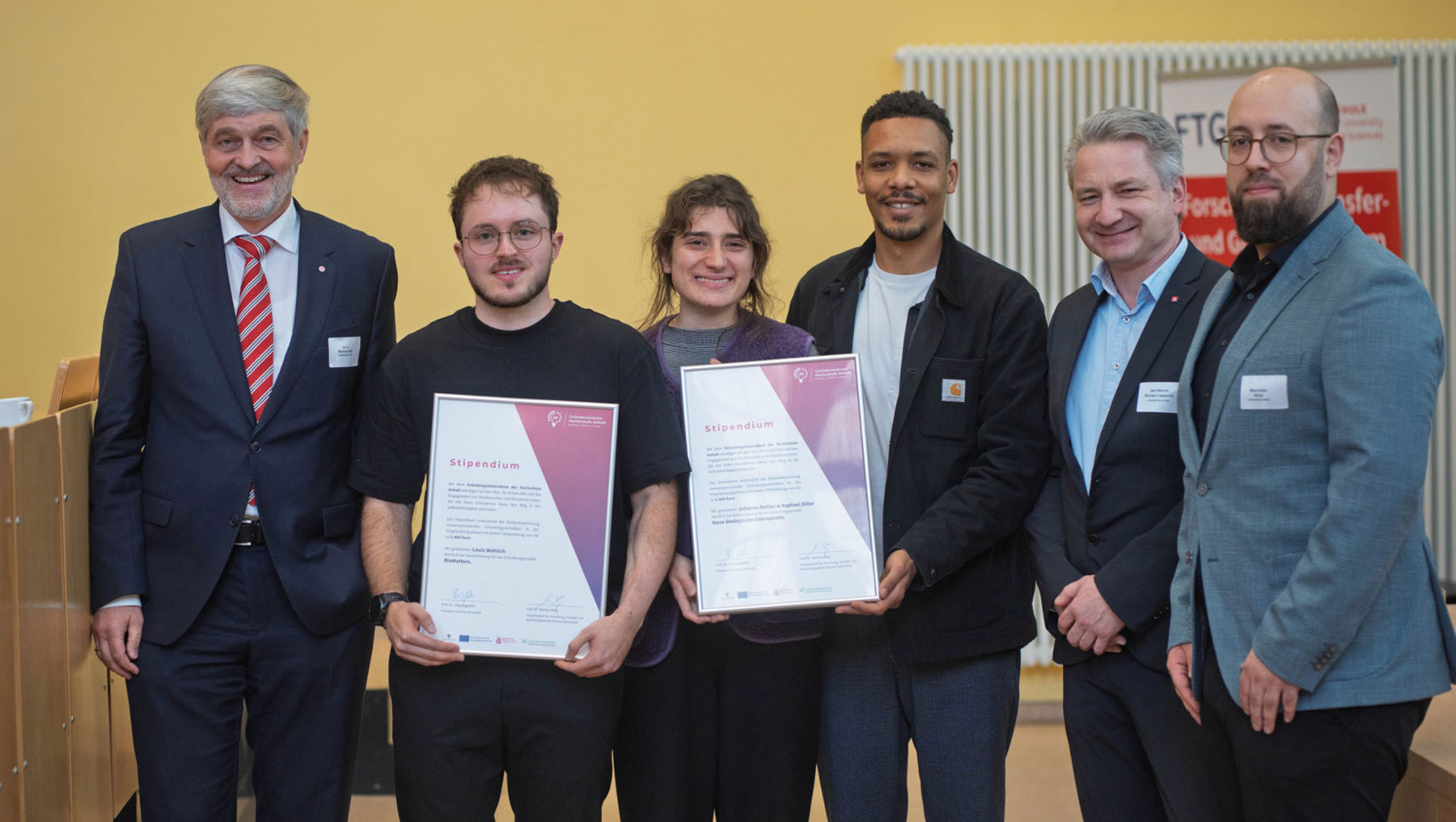Vizepräsident Prof. Dr. Markus Holz übergibt im Beisein von weiteren Hochschulangehörigen den Preis an Stipendiaten.