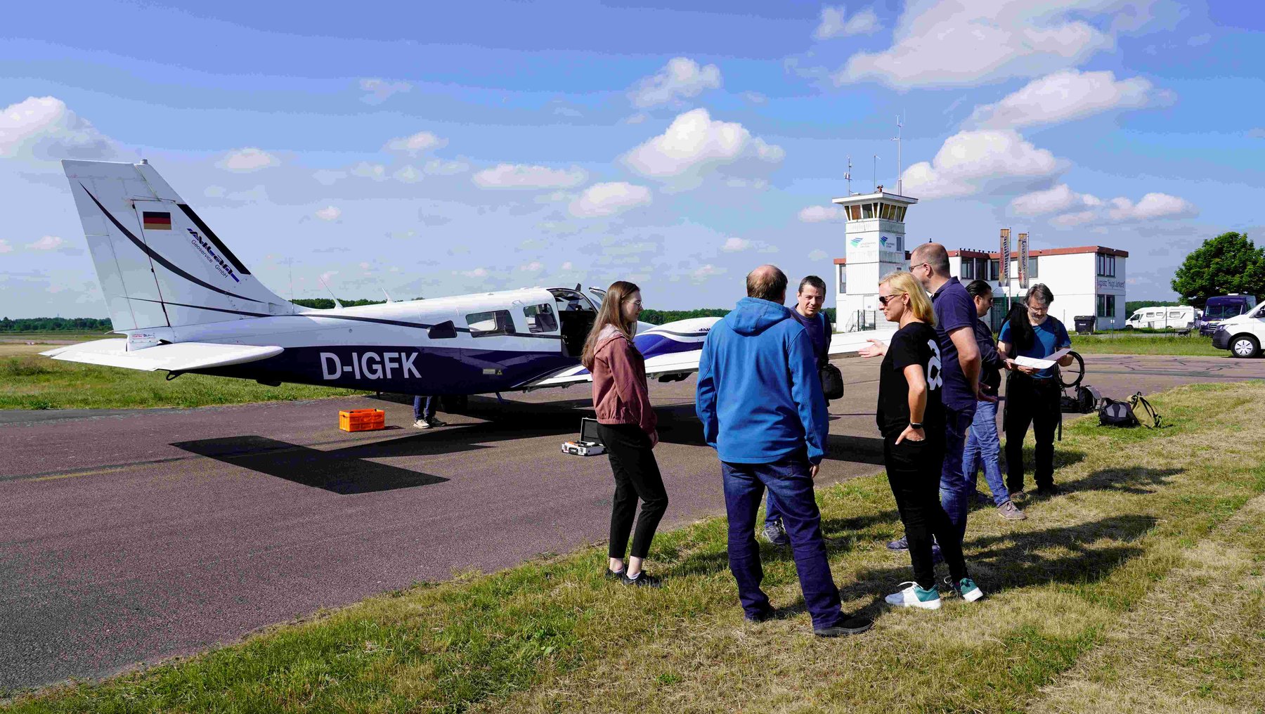Gruppe von Personen auf einem Flugplatz mit Terminal und Kleinflugzeug zeigt Forschungsgruppe der Hochschule Anhalt bei Tests mit Telops Hyper-Cam Airborne Mini