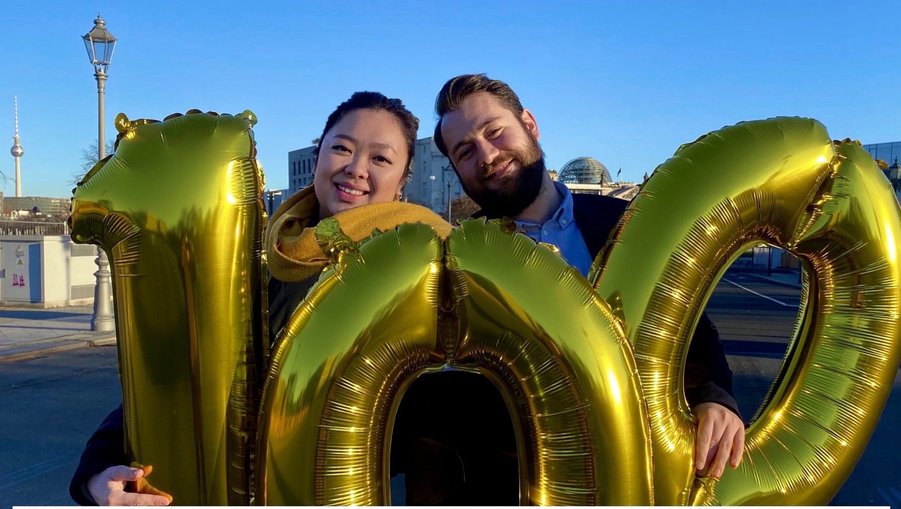 Studierende mit goldenem "100"-Luftballon