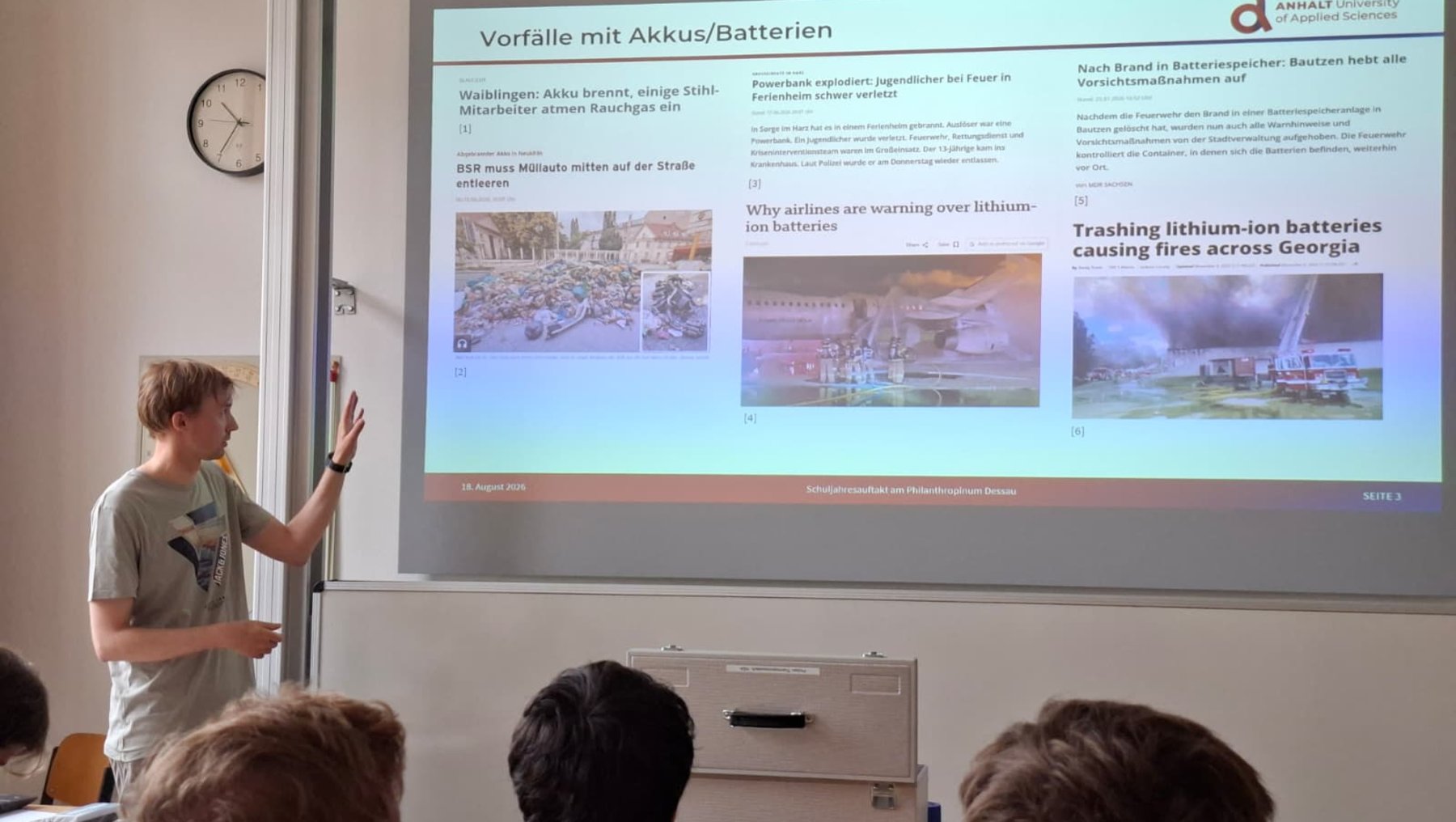 Ein Vortragender steht vor einer Präsentation zum Thema Vorfälle mit Akkus und Batterien. Die Folie zeigt Gründe für Brände durch Lithium-Ionen-Batterien, wie unsachgemäße Entsorgung oder Beschädigung, sowie Beispiele aus der Praxis, etwa Brände in Müllcontainern und bei Flugzeugen.