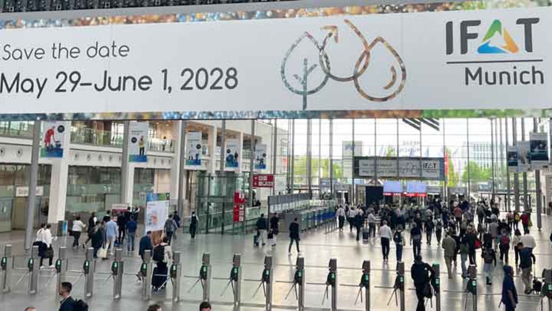Plakat zur IFAT München 2028 mit Datum **29. Mai bis 1. Juni 2028**, das eine Messe für Umwelttechnologie ankündigt. Im Hintergrund viele Besucher in einer Messehalle.