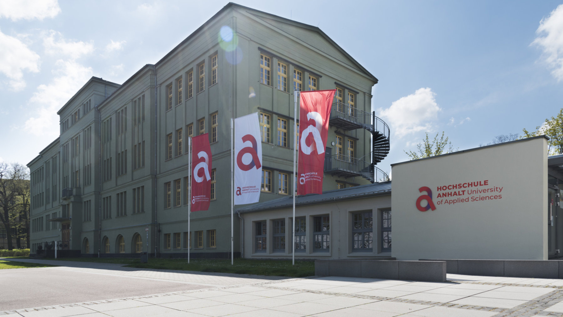 Das Grüne Gebäude und das Gebäude des Studierenden-Service-Centers. Fahnen wehen.
