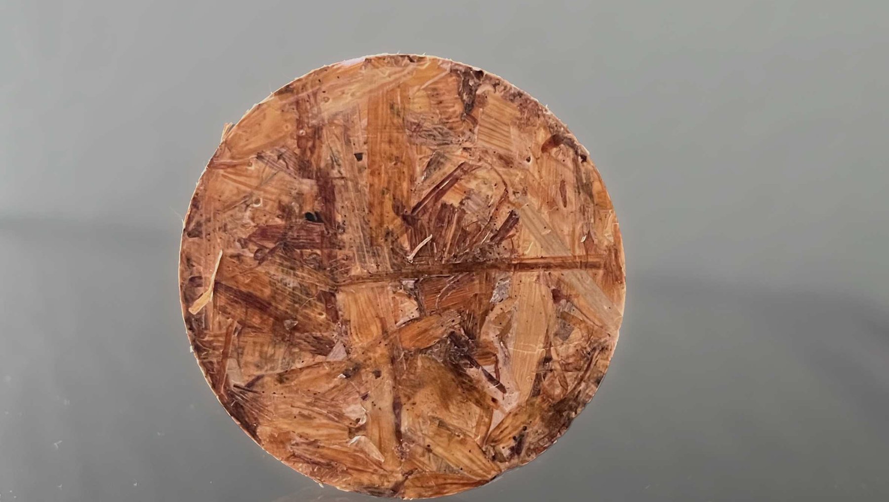 Rundes, leicht gebogenes Holzbrett mit vier tiefen, kreuzförmig angeordneten Rillen, die durch natürliche Maserung und eine leicht raue Oberfläche geprägt sind.