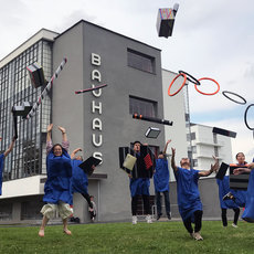 Verkleidete Absolventen springen vor dem Bauhaus