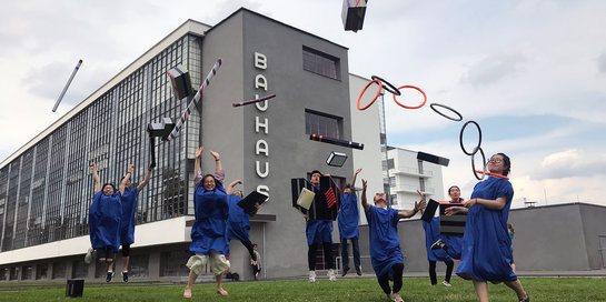 Verkleidete Absolventen springen vor dem Bauhaus