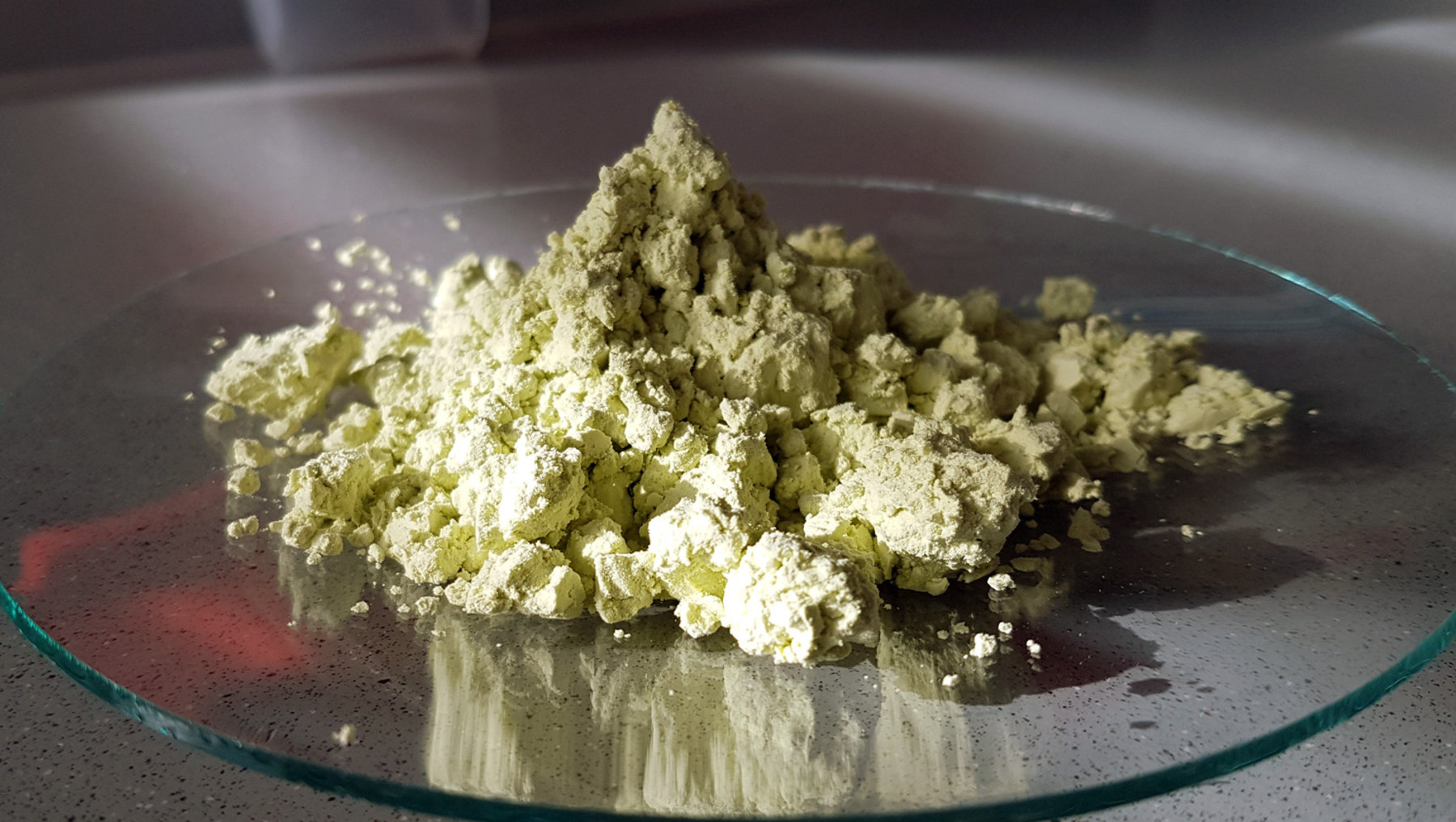 The image displays what appears to be a quantity of dried, light green, chunky herb or plant material piled on a reflective surface.このほかの詳細内容 PV represents it in a clustered form. alınmamasını sağlamak için.