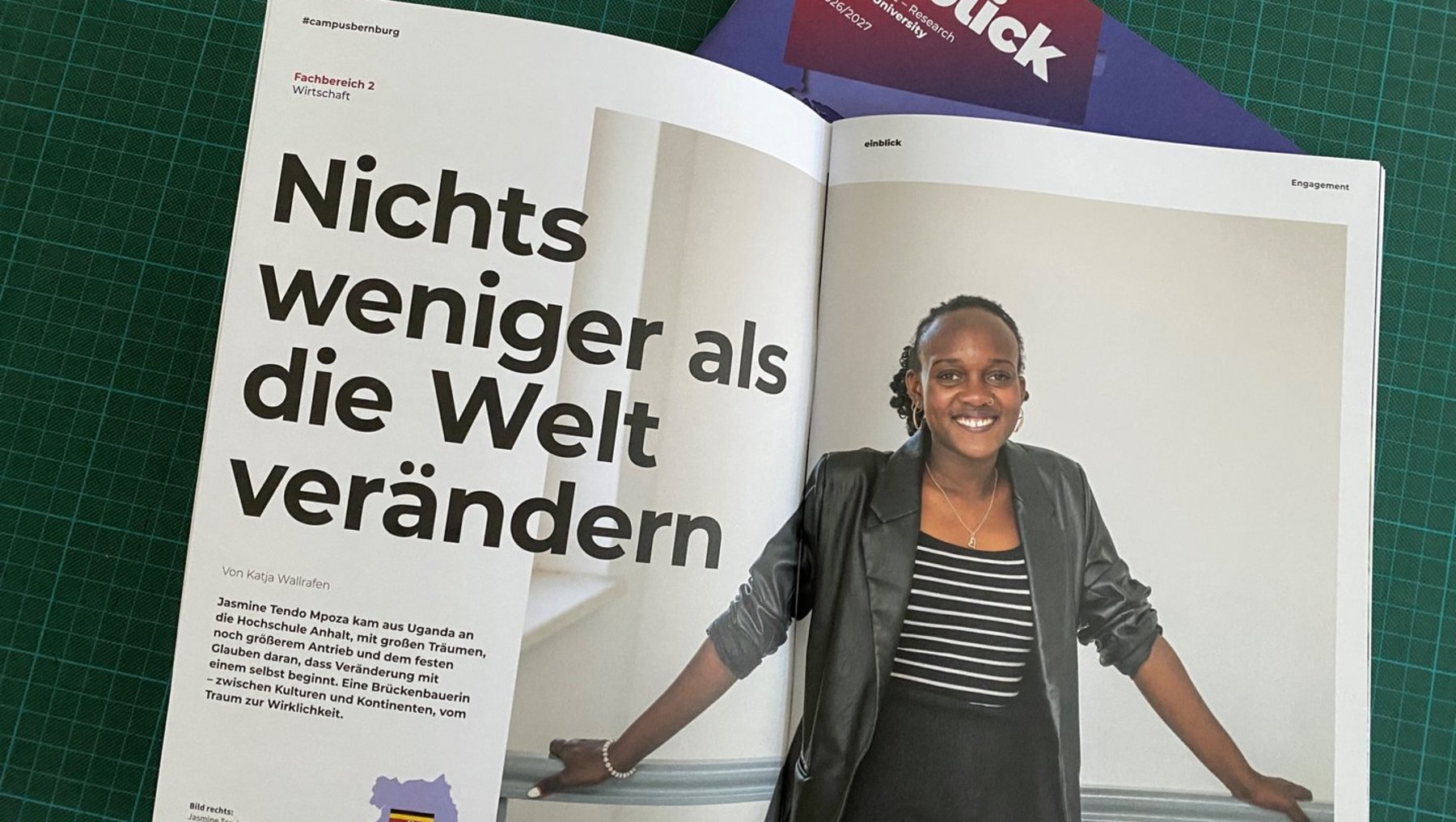 Zeitschrift „einblick“ mit Artikel über eine lächelnde Frau, die vor einem Fenster steht. Überschrift lautet: *„Nichts weniger als die Welt verändern“*.