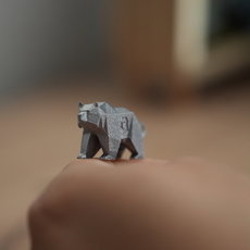 Ein Origami-Bär aus dunklem Papier sitzt auf einer Handfläche und blickt nach vorne.