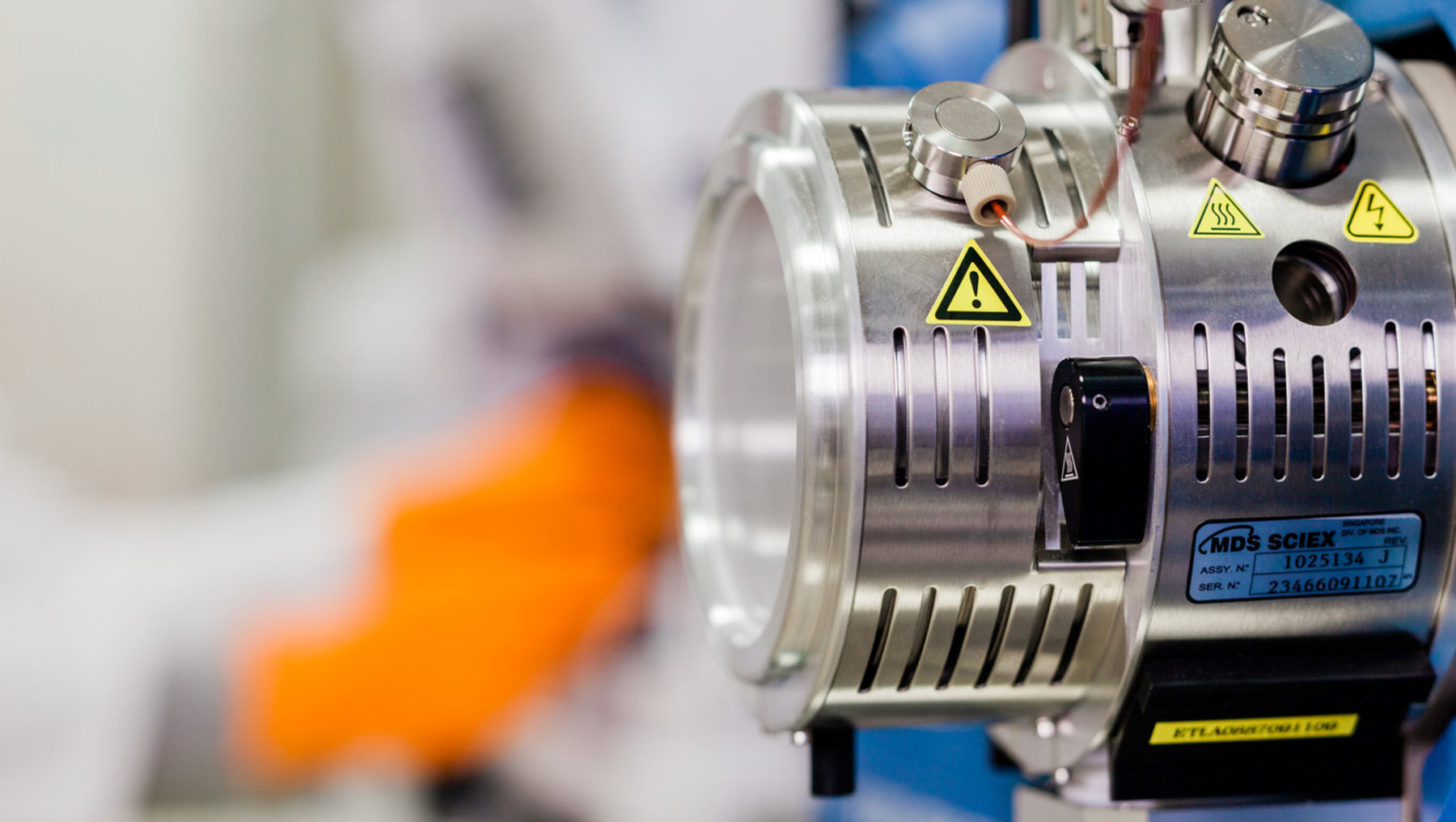 Diese Abbildung zeigt eine Industriepumpe mit Warnaufklebern (gelbe Triangles mit Ausrufezeichen), Markierungen des Herstellers "KDB.SCHEX" und einem Schutzgehäuse, teilweise aus Metall