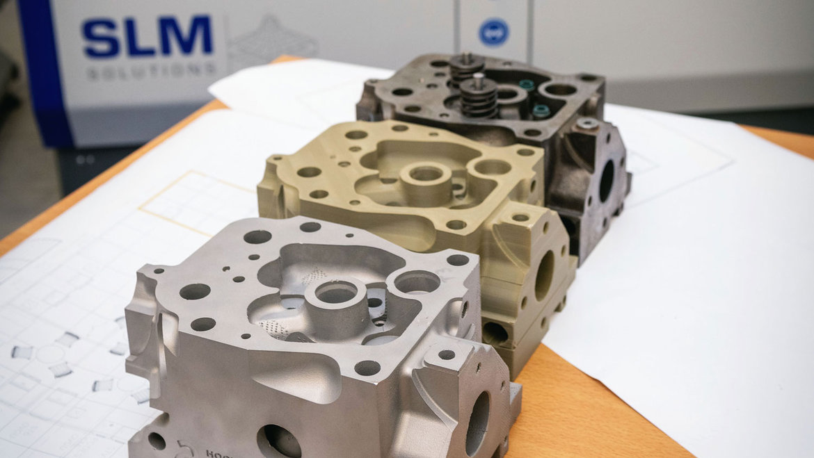 Drei Motor-Komponenten, vermutlich Zylinderkopf und -block, aus Metall, übereinander gestapelt. Die Teile zeigen Bohrungen und komplexe Gussstrukturen, typisch für Motorenbauteile.