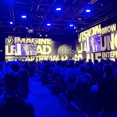 Großer Kongresssaal mit Publikum, in dem auf einer großen Leinwand die Worte „Imagine LA, Vision Grow, Launch, Innovation Artificial Intelligence, Social Entreprene“ in hellen Buchstaben projiziert werden.