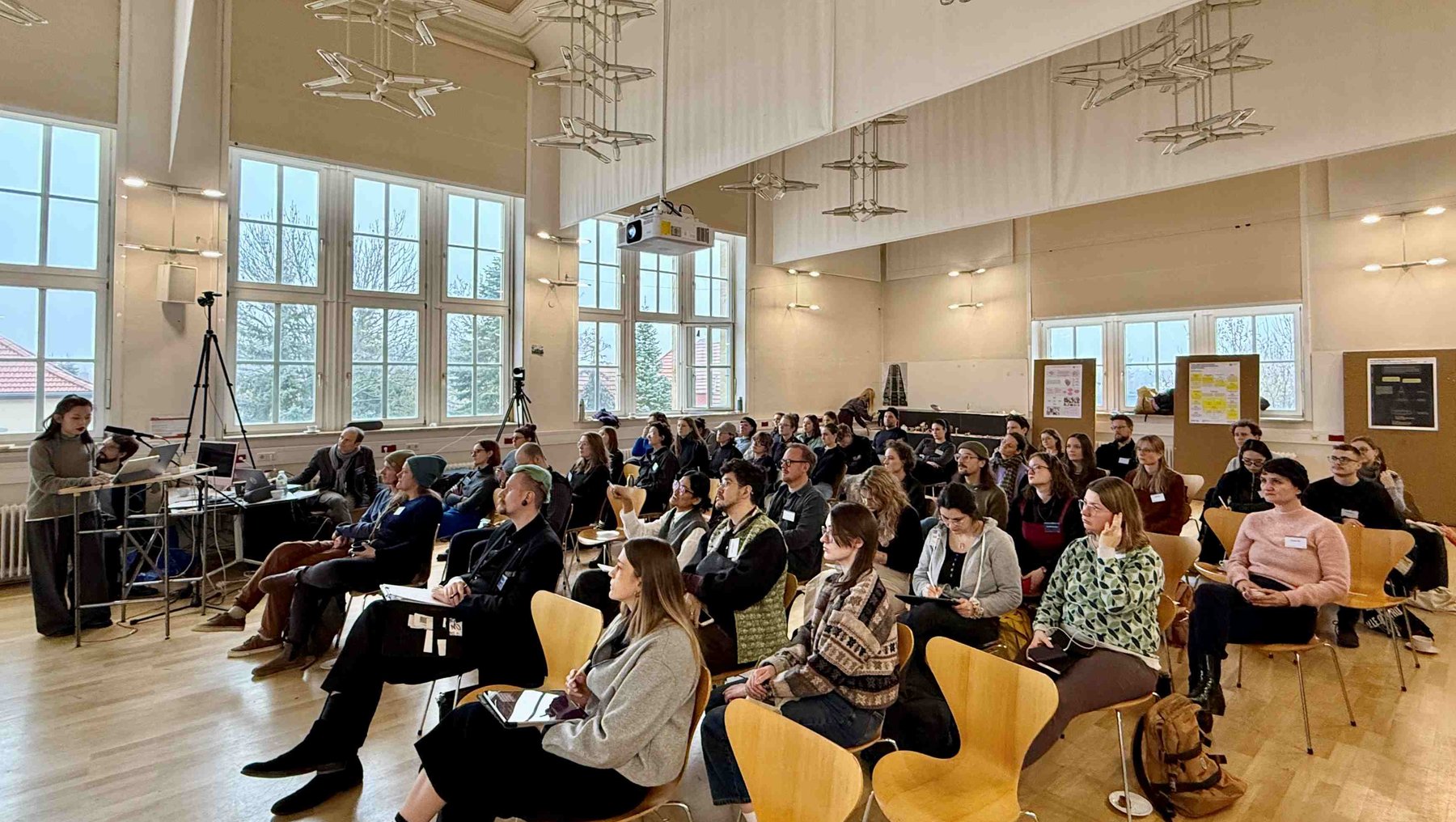 Symbolbild Promovieren im Design zeigt Vortrag mit Publikum in einem historischen Saal am Bauhaus Dessau