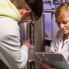 Zwei Studierende in Laborkitteln mit Klemmbrett