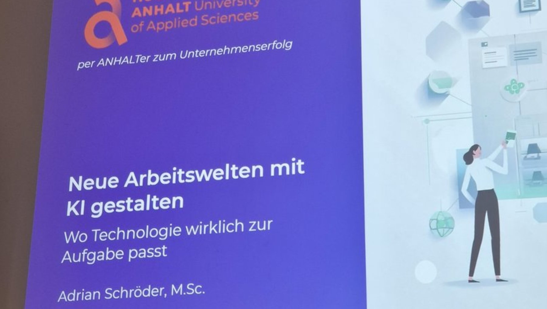Vortragsfolie der Hochschule Anhalt mit dem Titel Neue Arbeitswelten mit KI gestalten. Gezeigt wird eine Person vor einem digitalen Bildschirm mit KI-Elementen wie Datenwolken und Symbolen für Technologie. Der Vortragende ist Adrian Schröder, M.Sc.