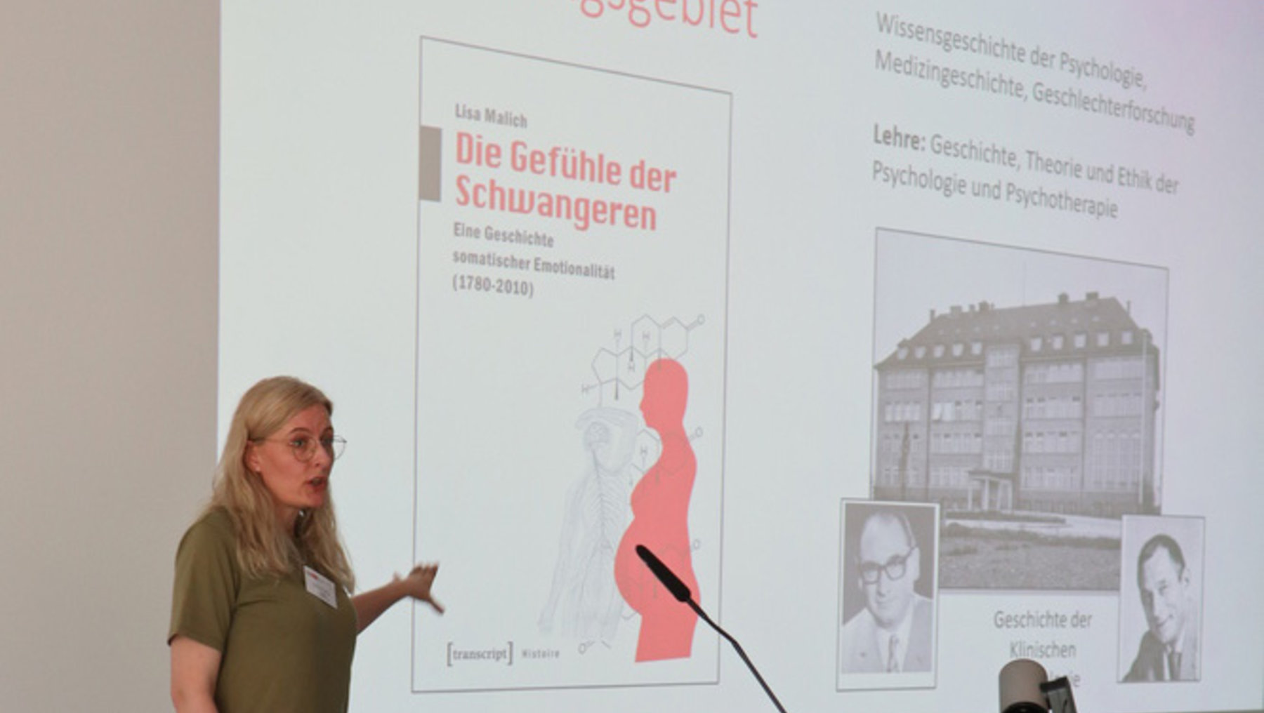 Eine Frau hält einen Vortrag über das Buch "Die Gefühle der Schwangeren" von Lisa Malich. Der Vortrag behandelt die Geschichte der Emotionalität Schwangerer von 1970 bis 2015. Im Hintergrund sind weitere Informationen und Bilder zu sehen, die das Thema unterstützen.