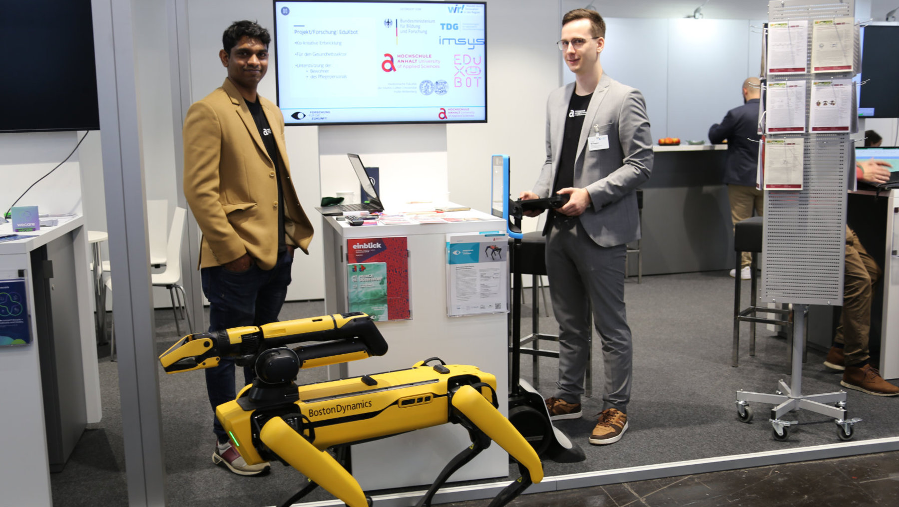 Subashkumar Rajanayagam und Nils Dohndorf mit Roboterhund Spot am Messestand.