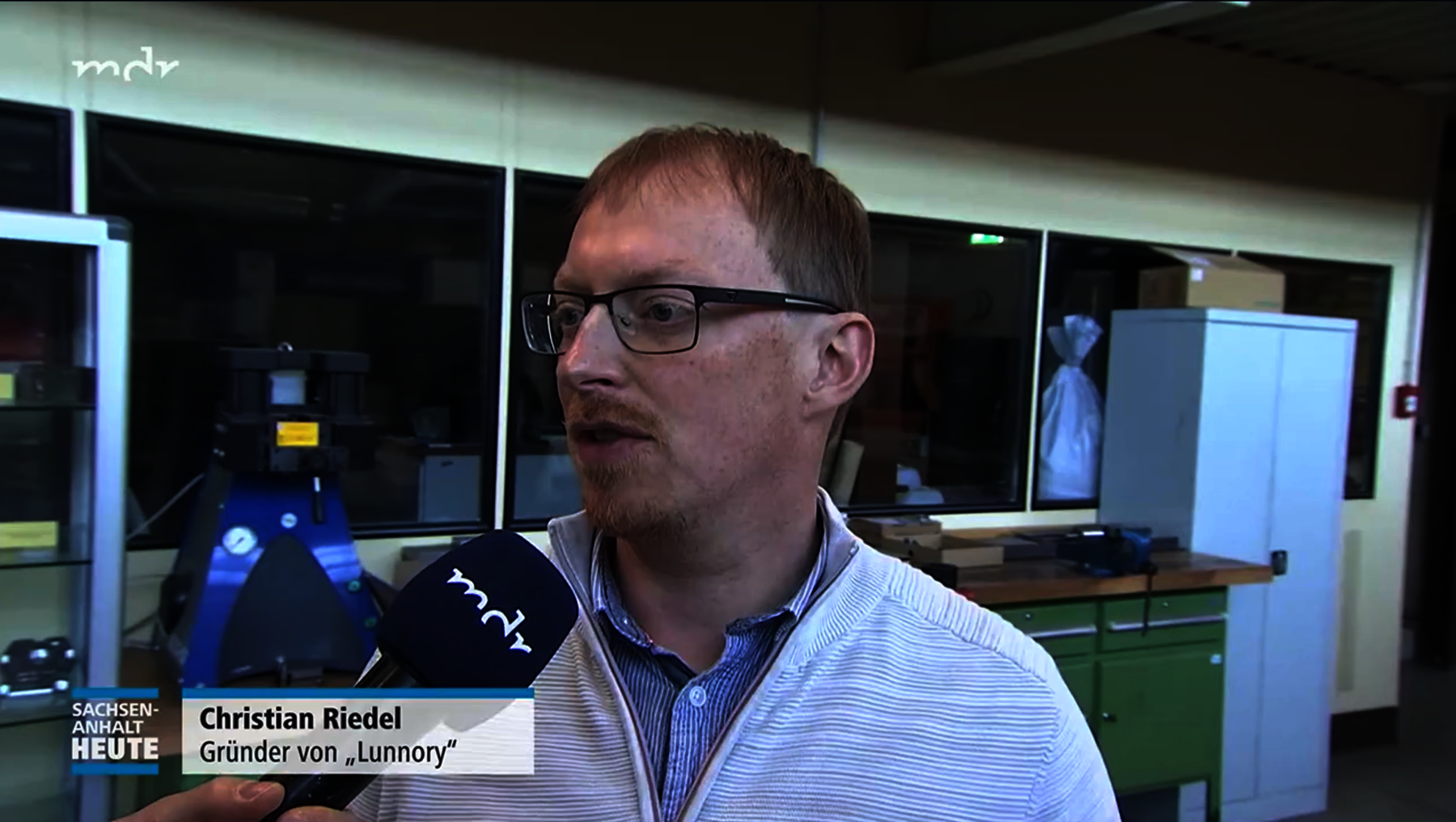 Ein Mann mit Brille und hellem Oberteil wird interviewt und hält ein Mikrofon. Er ist Christian Riedel, Gründer von „Lunnory“.