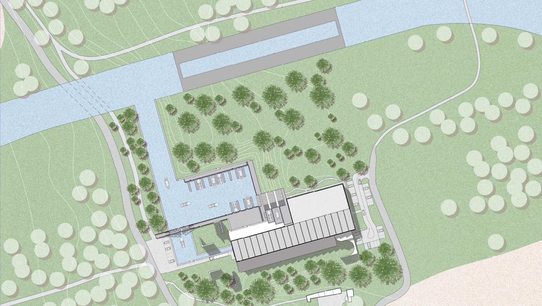 Luftbild eines Gebäudekomplexes mit zentralem Hauptgebäude, umgeben von Grünflächen und Bäumen. Im Hintergrund ein Fluss mit Uferweg und Brückenverbindung. Parkplätze und Zufahrtsstraßen befinden sich links und unten.