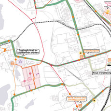 Straßenkarte mit markierten Buslinien in verschiedenen Farben, darunter eine Hauptverkehrsachse mit Haltestellen und Umsteigepunkten im Zentrum, umgeben von Wohngebieten und Gewerbegebieten.