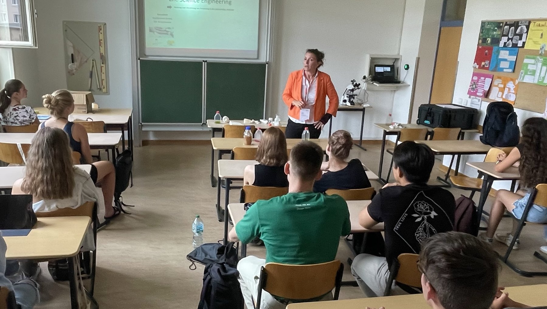 Ein Vortrag im Klassenzimmer zum Thema „Life Science Engineering“. Eine Person steht vorne und präsentiert, während etwa 15 Zuhörer auf Stühlen sitzen und aufmerksam zuhören.