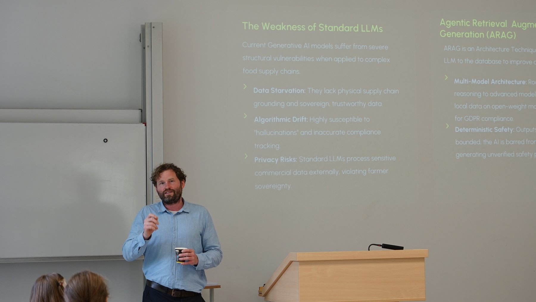 Ein Mann steht an einem Podium und hält einen Vortrag zum Thema Agentic Retrieval versus generative KI. Hinter ihm ist eine Präsentation mit Folie zu sehen, die Schwächen klassischer Sprachmodelle wie Datenverzerrung, Algorithmus-Death und Compliance-Risiken auflistet sowie Vorteile von ARAG (Agentic Retrieval Augmented Generation) wie Multi-Model-Architektur und datenschutzkonforme Sicherheit betont.