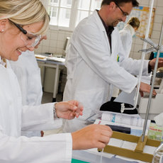 Professor und Studentin mit weißen Kitteln im Labor