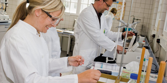 Professor und Studentin mit weißen Kitteln im Labor