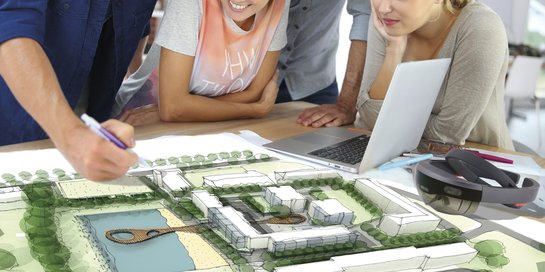 Studierende arbeiten an einem Lageplan mit Bäumen und Häusern
