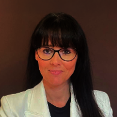 Diese Person trägt eine Jacke, eineerviewazy Brille mit Büro-Kleidung und kurz-Schwarze-Haare mit mittlerem Ton.
Sie ist eine attraktive, lächelnde Frau mit seriösem, professionellen Auftreten.