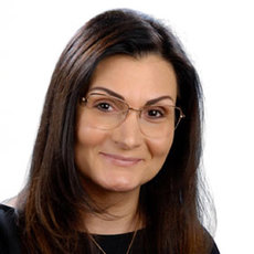 Diese Bild zeigt ein Porträt einer Person mit mittellanger, dunkler Haarpracht und einer durchsichtigen Brille.

Beschreibung:
Eine lächelnde Frau in mittlerer Altersgruppe blickt direkt in die Kamera. (Bild ohne unnötige Details, nur Hauptmerkmalen beschreibend.)