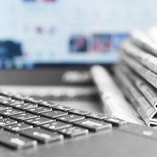 "Auf dem Bild ist eine Laptop-Tastatur zu sehen, auf der ein Stapel zusammengelegte Zeitungen oder Dokumente liegt. Die Tastatur ist im Vordergrund scharf, während die Zeitung unscharf im Hintergrund ist. \]"__