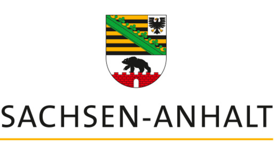 The image features the coat of arms of Saxony-Anhalt, Germany. It includes a bear walking over a red wall, a black eagle on a yellow and black striped background, and the text "SACHSEN-ANHALT" written below. The coat of arms represents the state of Saxony-Anhalt.