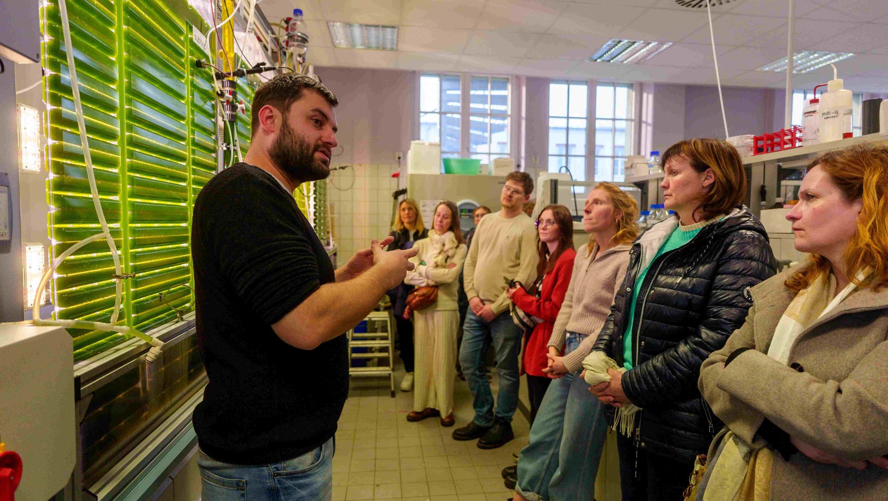 Gruppe von Personen in einem Labor zeigt Auftakt des Netzwerks Algahub und Präsentation eines Algenbioreaktors zur Produktion von Algen-Öl