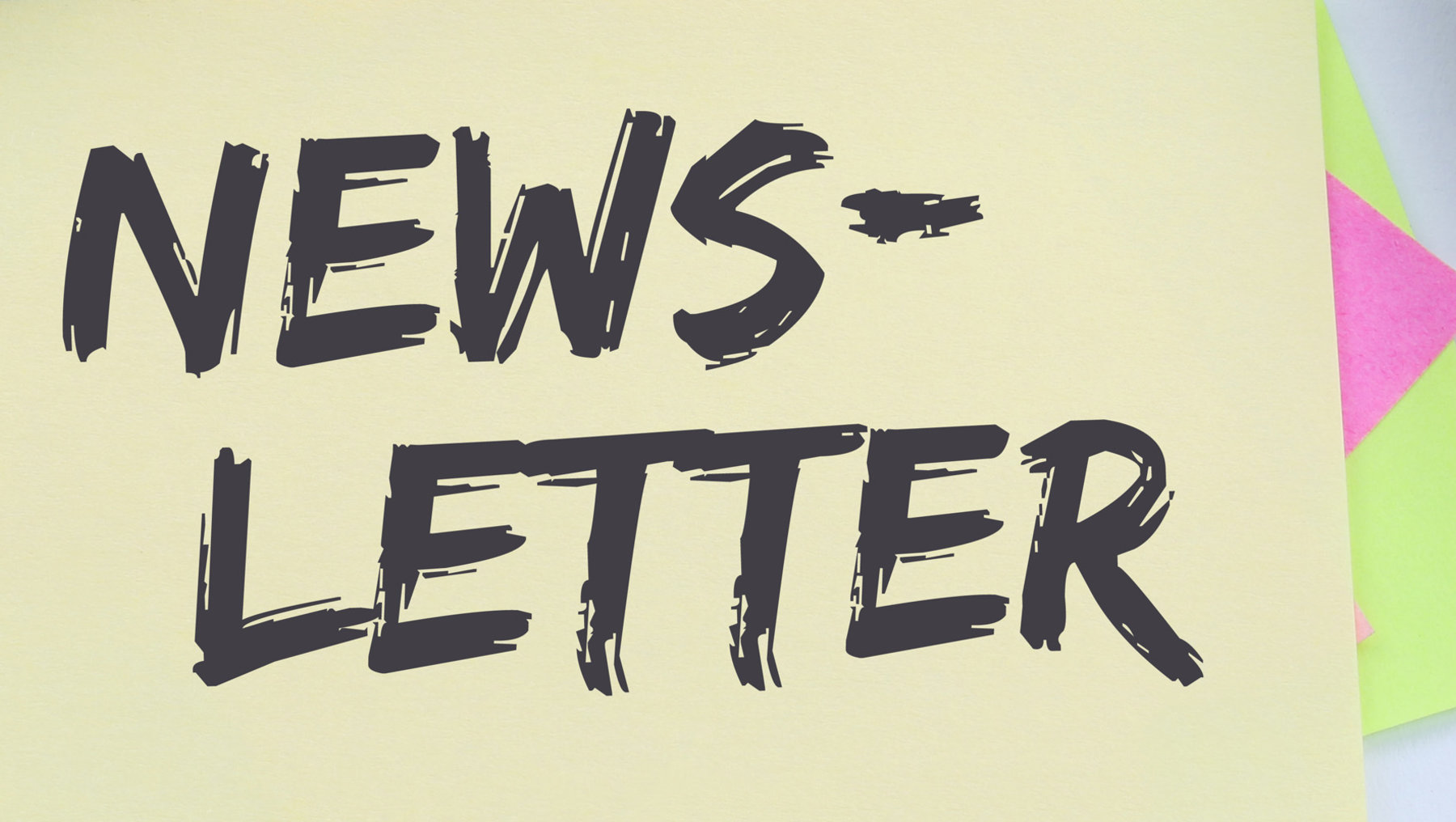 Gelbes Post-it mit handschriftlich geschriebenem, leicht schräg gehaltenem Text „NEWSLETTER“, daneben ein Handy und weitere bunte Notizzettel.
