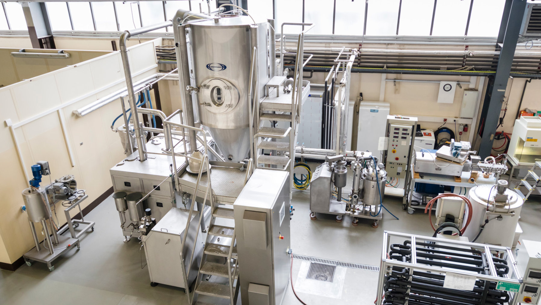 The image displays a modern, industrial brewing facility with large brewing kettles, fermentation tanks, and associated stainless steel brewing equipment used for the production of beverages such as beer. Такође су приказане хо 정도는 контроли delegate machines and pipelines.